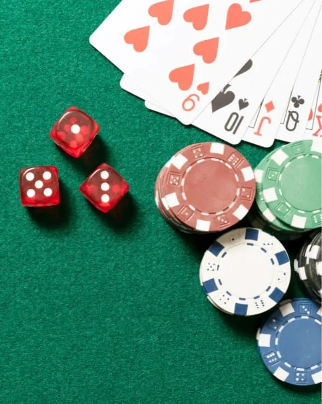 overhead shot of green card table with poker chips and dice and a hand of playing cards showing a straight