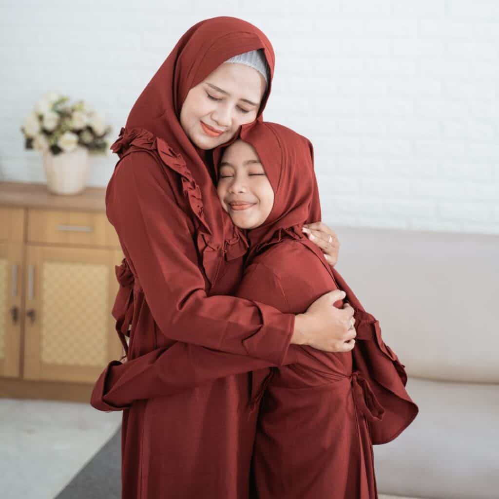 a muslim mom and daughter hugging each other in a living room