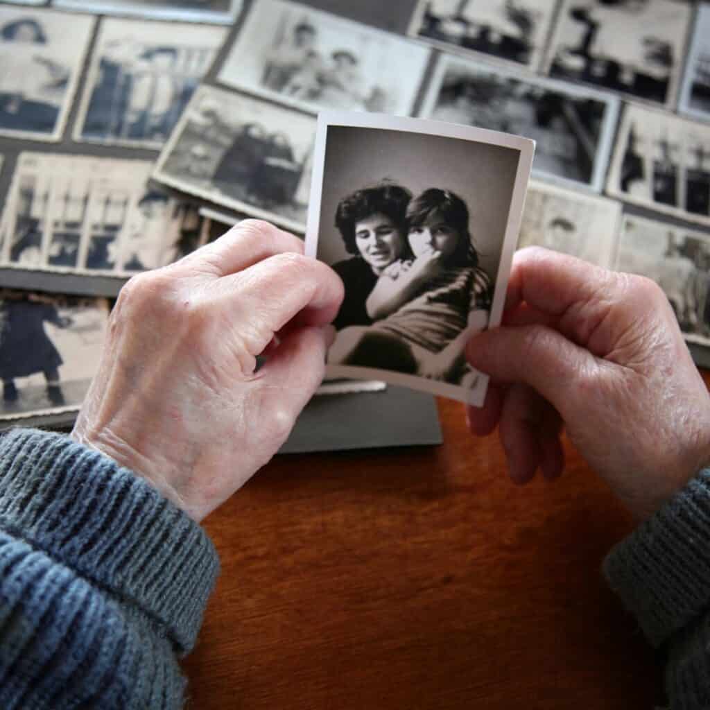 old woman's hands holding an old black and white picture of her and her daughter