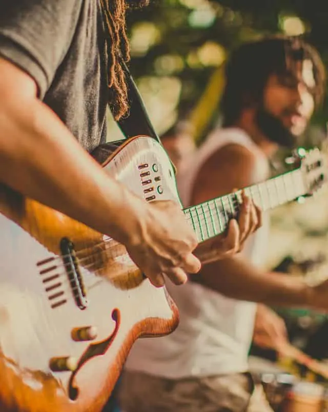 Close up shot of musician holding an electric guitar with drummer standing close behind