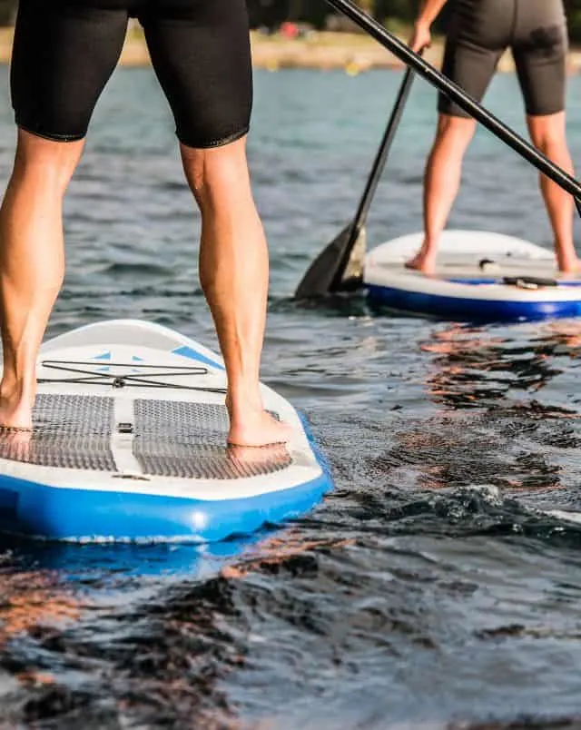 Get the most out of your adult entertainment in Wisconsin Dells, view of the legs of people standing on paddle boards in a calm body of water