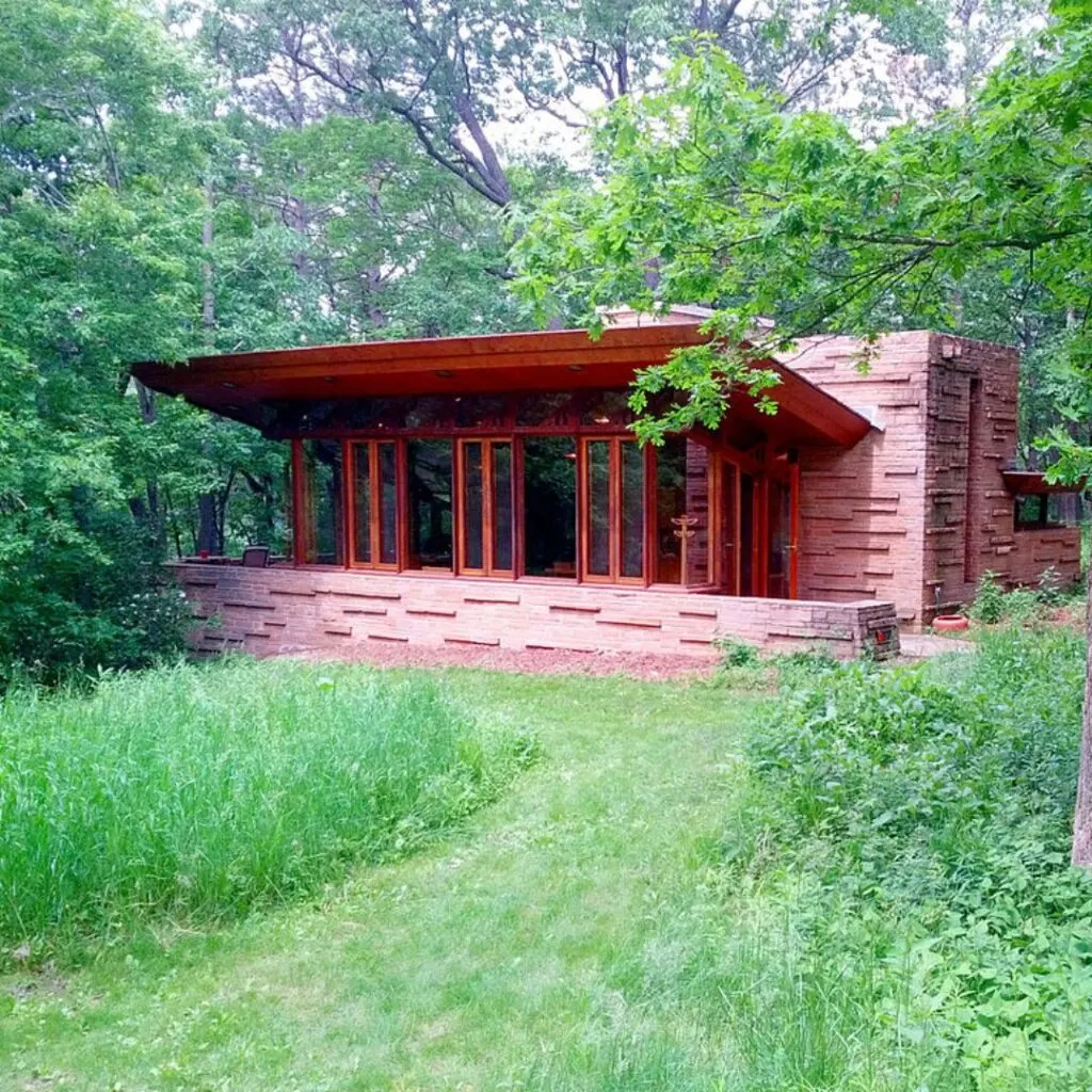 a small cabin sitting in the middle of a wooded area filled with grass and trees