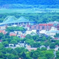 fun things to do in La Crosse Wisconsin, view looking across a valley with buildings and a bridge surrounded by green trees with a large green hill behind