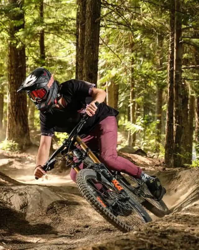 Where to go biking in Door County, Person on mountain bike zooming around a bend on a dirt track at an impressive angle with dense green forest behind