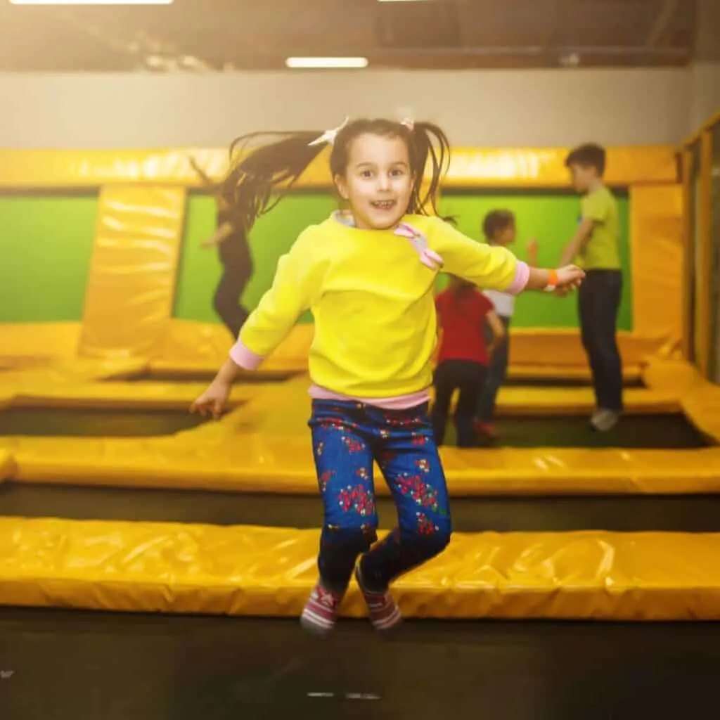 a girl jumping on a trampoline in an indoor play area