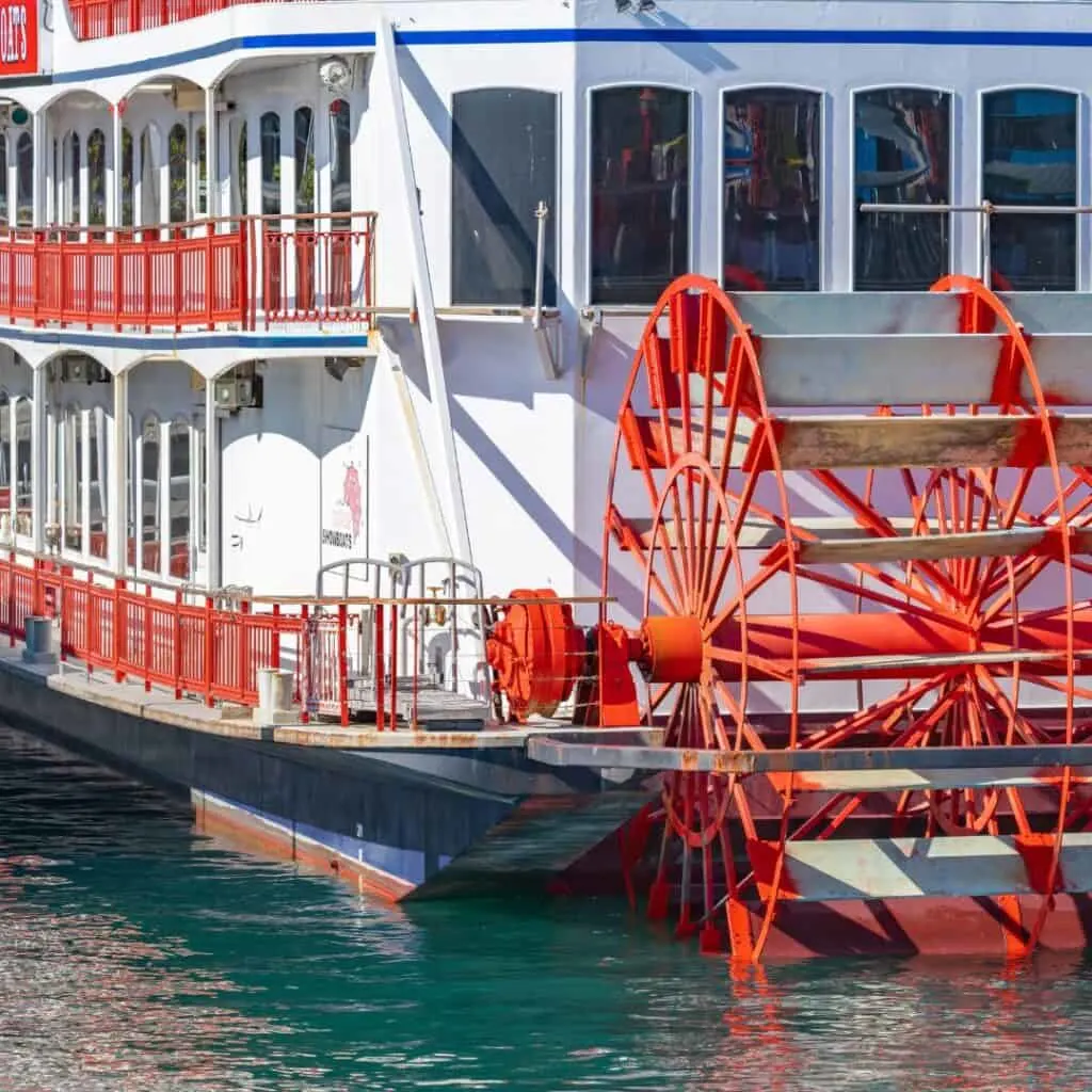 a closeup of red and white water wheel boat on the water