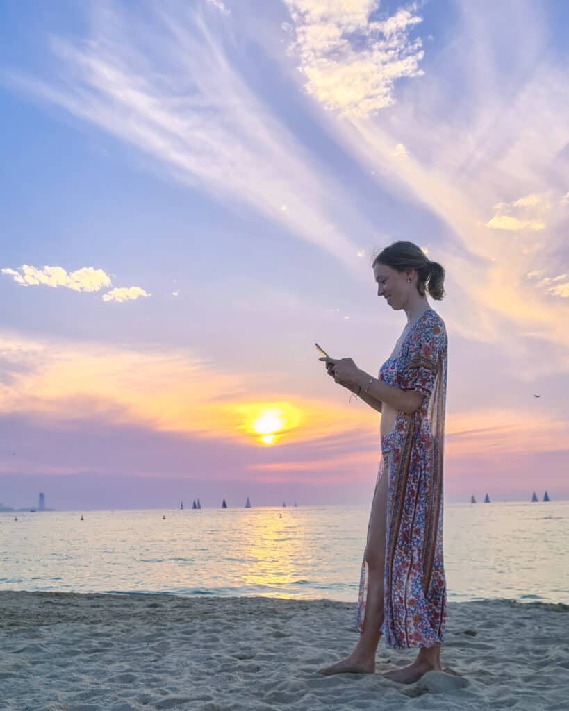 travel blogger at beach during sunset with phone