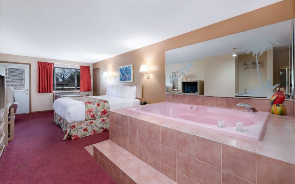 Wisconsin Dells romantic hotels, interior of a hotel room with pink and red decor, room has large bed and bathtub