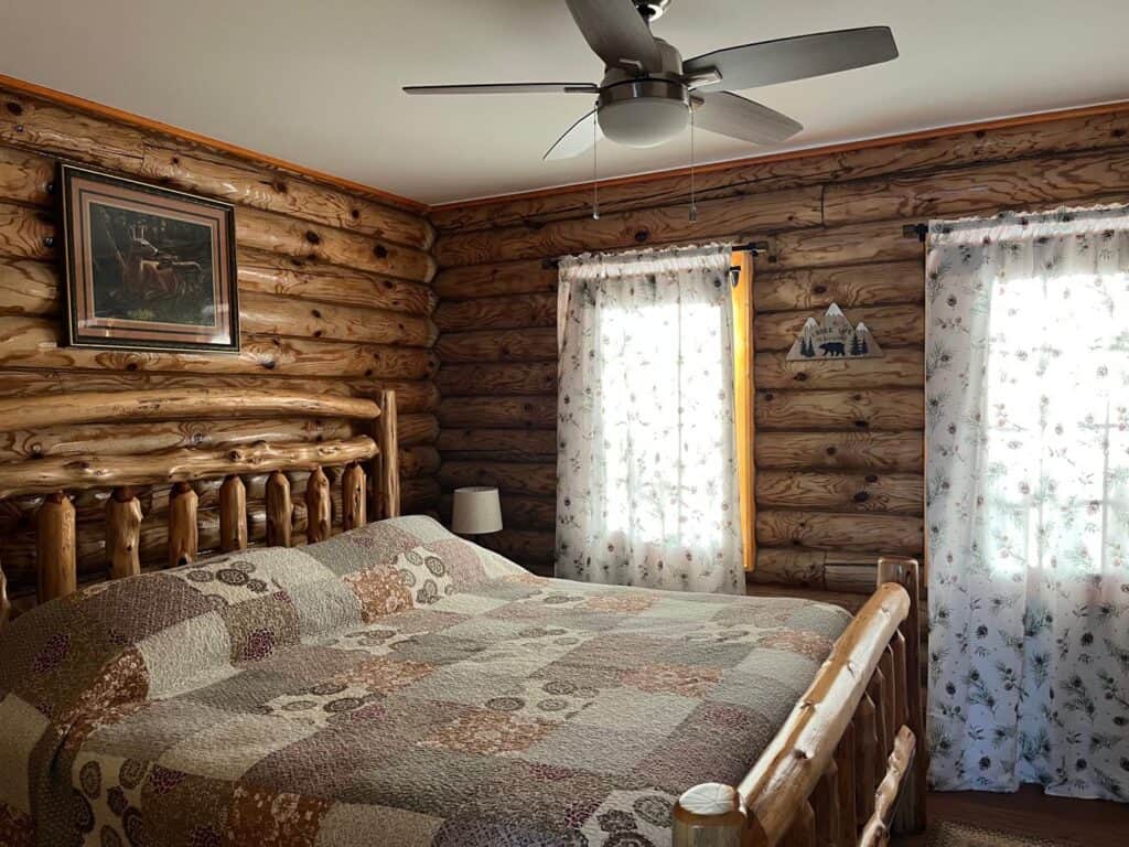 Wisconsin Dells resorts for couples, interior of a room with walls made of wooden logs and a with bed made of wood, and a ceiling fan