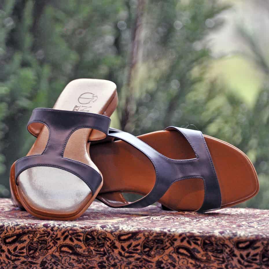 vegan walking sandals, black sandals on table with one on its side and one propped against it