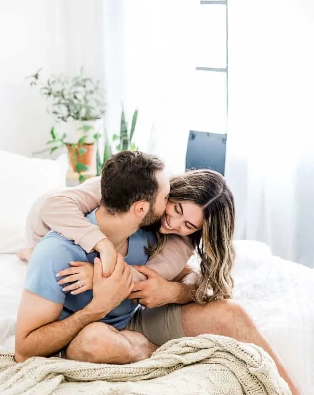 a couple embracing each other affectionately on a bed at one of the most romantic hotels in Door County