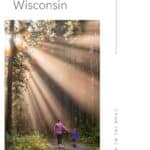 Pin with image of an adult and child holding hands and walking along a forested path partially lit up by sun rays, text above image reads: 10 best things to do in Oshkosh, Wisconsin