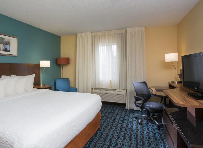 a cozy bedroom with a desk and tv at Fairfield Inn Suites by Marriott Oshkosh Wisconsin - 14 Cool Hotels in Oshkosh for All Budgets