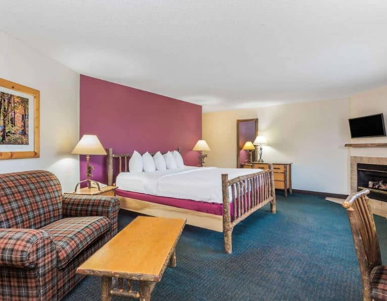 a cozy room at AmericInn by Wyndham Wisconsin Dells with bed sofa and a fire place - 10 Great Pet-Friendly Resorts in Wisconsin Dells