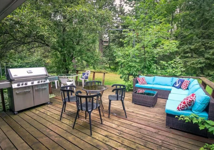 lovely porch surrounded by woods with a grill and garden sofa at Beautiful Home on Madeline Island Apostle Island Wisconsin - 14 Unique Airbnbs in Apostle Islands