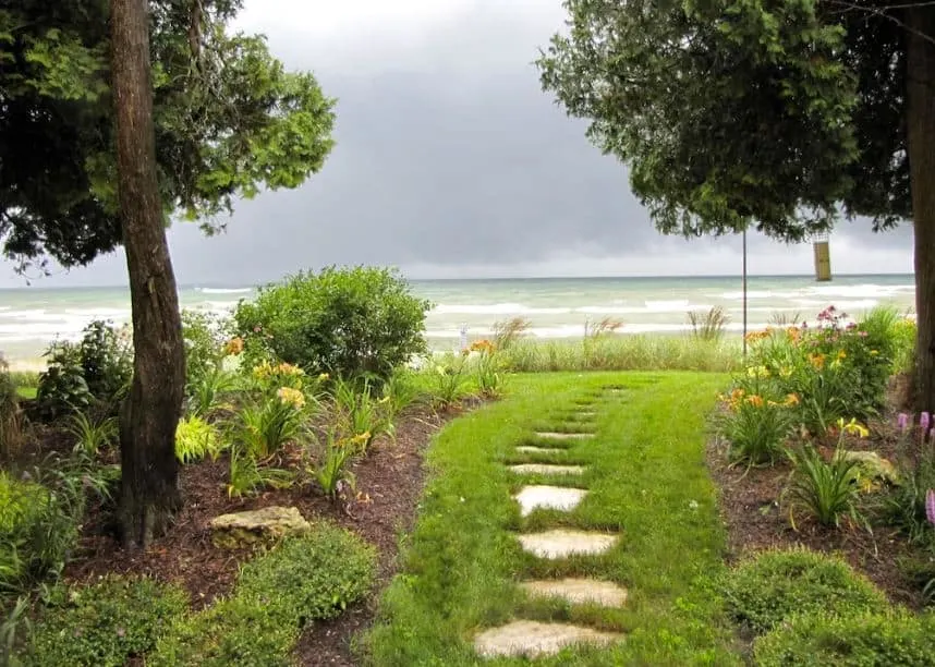 grassy path with tile blocks to the lake, flowers, and trees