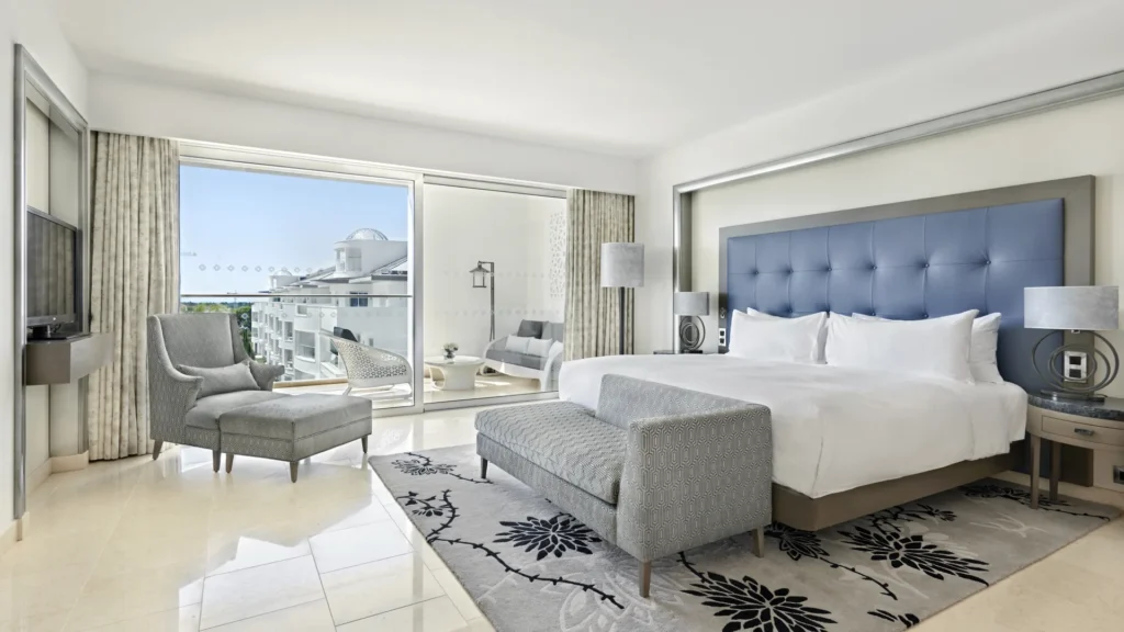 Why not travel 5-star all-inclusive Algarve, spacious hotel room with tasteful modern colour scheme in grey and cream with large double bed and sofa chairs with large sliding glass door leading to balcony