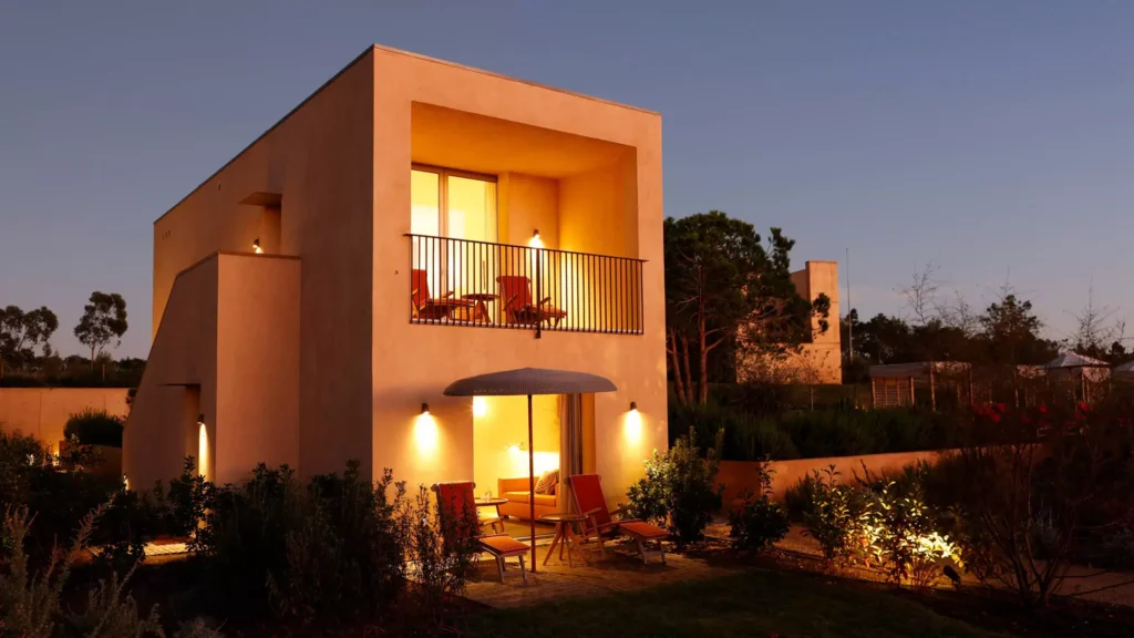 Stay in some Algarve 5-star hotels on your next vacation, view of hotel exterior at dusk with bright lights illuminating the outdoor balcony and patios areas of a two storey stone building with surrounding garden areas