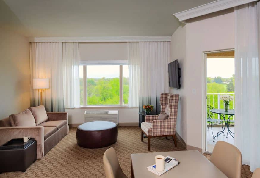 a cozy living room with a sofa, tv and balcony at The Ingleside Hotel, Pewaukee