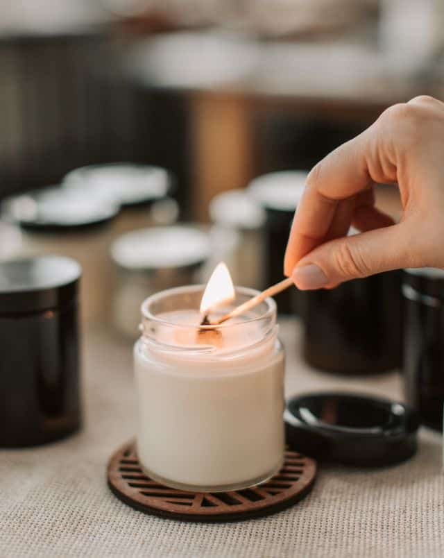 things to do in Milwaukee for couples, close up shot of a person's hand holding a lit match as they light up a scented candle