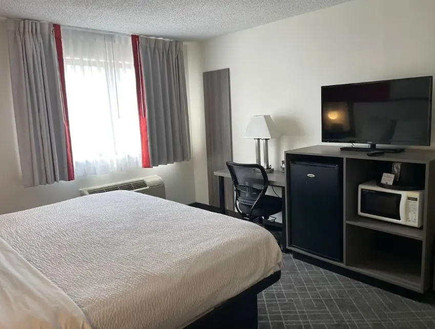 bedroom with tv, microwave, fridge and desk at Ramada by Wyndham, Waupaca