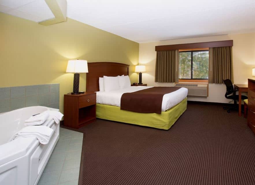 cozy bedroom with bathtub and desk at Cobblestone Hotel & Suites, Wisconsin Rapids