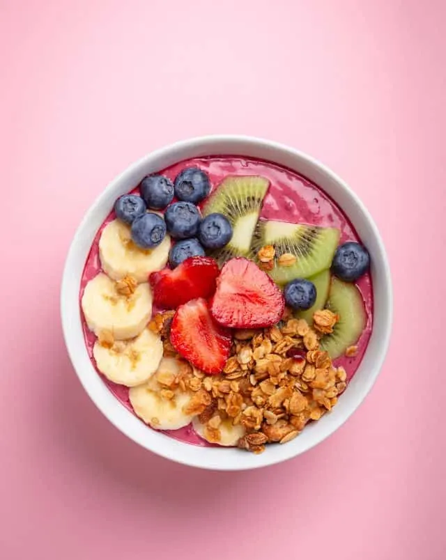find vegan options in Milwaukee, best best vegan restaurants Milwaukee has to offer, Overhead shot of a breakfast bowl containing sliced bananas, strawberries, kiwi fruit, blueberries and toasted nuts all on a bed of berry yoghurt