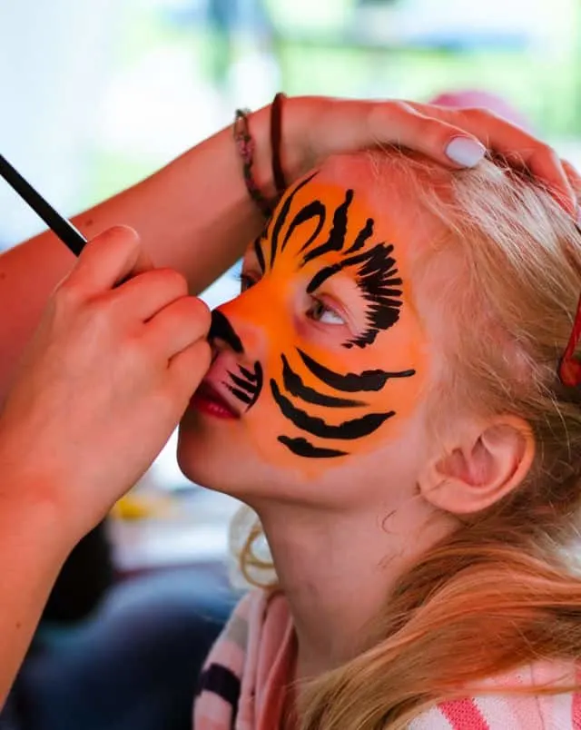 fall festivals Northern Wisconsin, Close up shot of child having their face painted in tiger colors and patterns