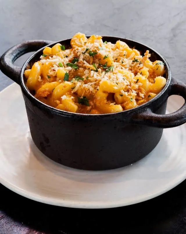 where to eat vegan in Milwaukee, Black cooking pot full to the brim with cooked pasta covered in grated cheese and herbs