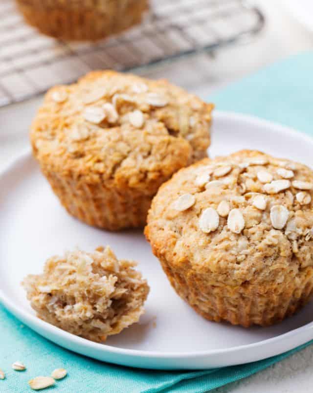 where to get the best vegan cupcakes in Milwaukee, Close up shot of two light brown muffins covered in sliced nuts with a small piece of a third muffin to one side all sitting on a white ceramic place