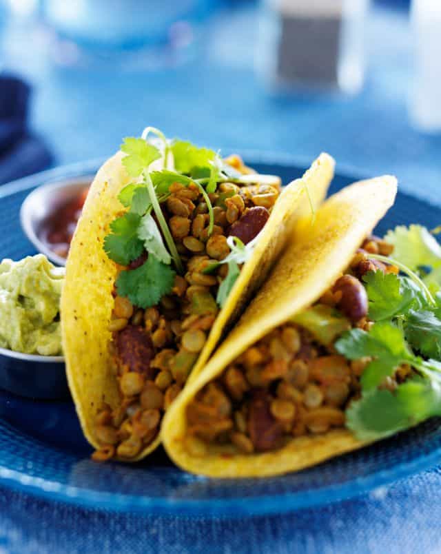 romantic restaurants in Milwaukee, Close up shot of a pair of tacos filled with beans and cilantro with a couple of small dips to one side all sitting on a blue ceramic plate