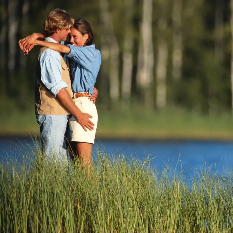 a couple hugging by a lake at one of the best places Where To Stay In Door County For Couples