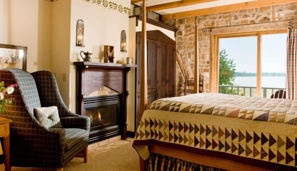 bedroom with cozy bed, fire place and lake view at the Blacksmith Inn On the Shore in Door County, Wisconsin