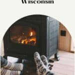 a pin with a couple heating their feet by the fire place at one of the best romantic winter cabins in Wisconsin