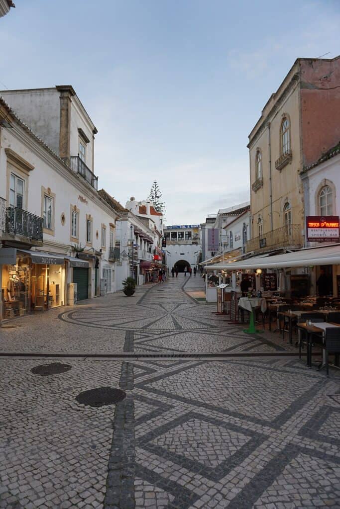 A city street at dusk with a lot of shops and restaurants in albufeira