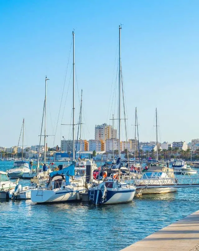 best things to do in Portimao, Collection of sailing boats moored in a river in front of a backdrop of apartment buildings all under a clear blue sky