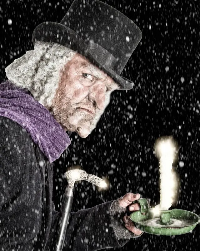 Milwaukee events in December, Image showing artistic representation of fictional character Ebenezer Scrooge from Charles Dickens' novel A Christmas Carol, seen here in a hat and scarf and holding a silver cane and a candle in a candle holder in the snow