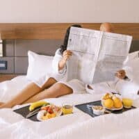 couple having breakfast in bed while reading the paper