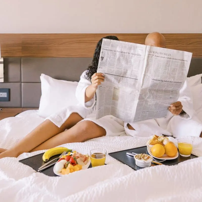 couple having breakfast in bed while reading the paper at one of the best romantic resorts in Wisconsin