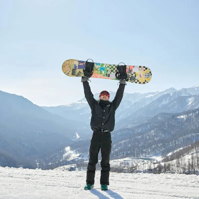 man holding his snowboard in the air around some of the best snowboarding resorts in Wisconsin