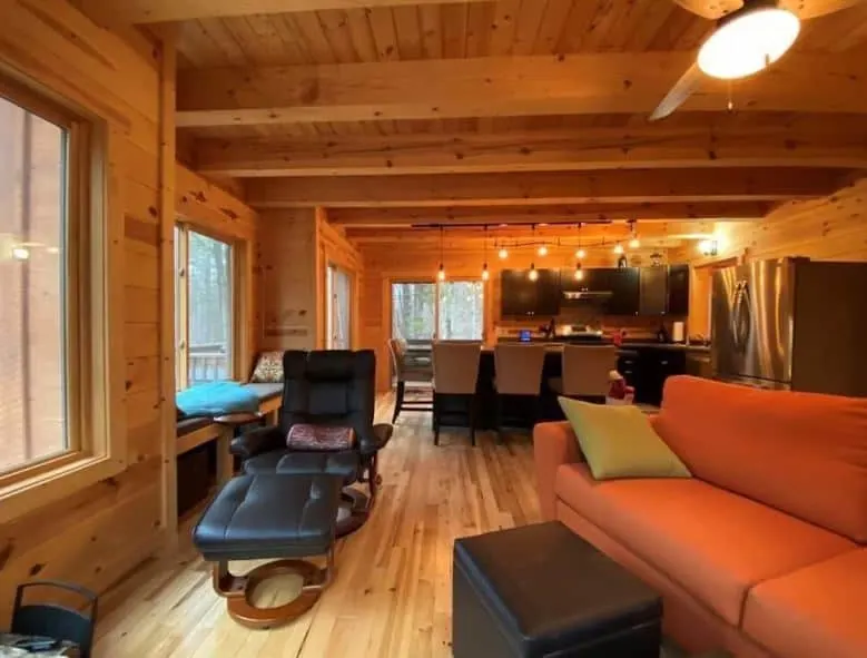 wooded living room with sofa and dining area at the Modern chalet nestled in the woods in Hayward, WI