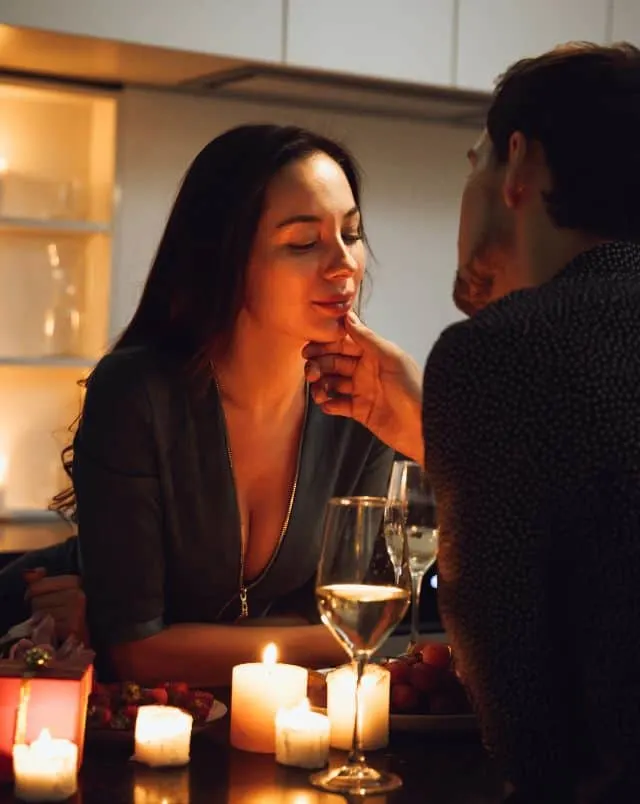 what to do in Milwaukee for couples, Two people having a candlelit dinner with one reaching romantically towards the face of the other over a couple of glasses of wine