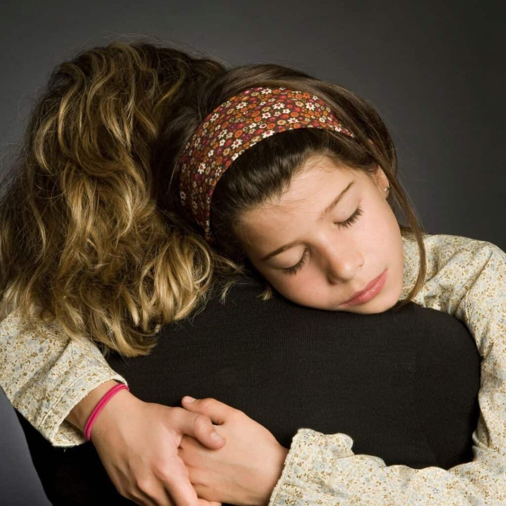 a sad child hugging tightly her mother