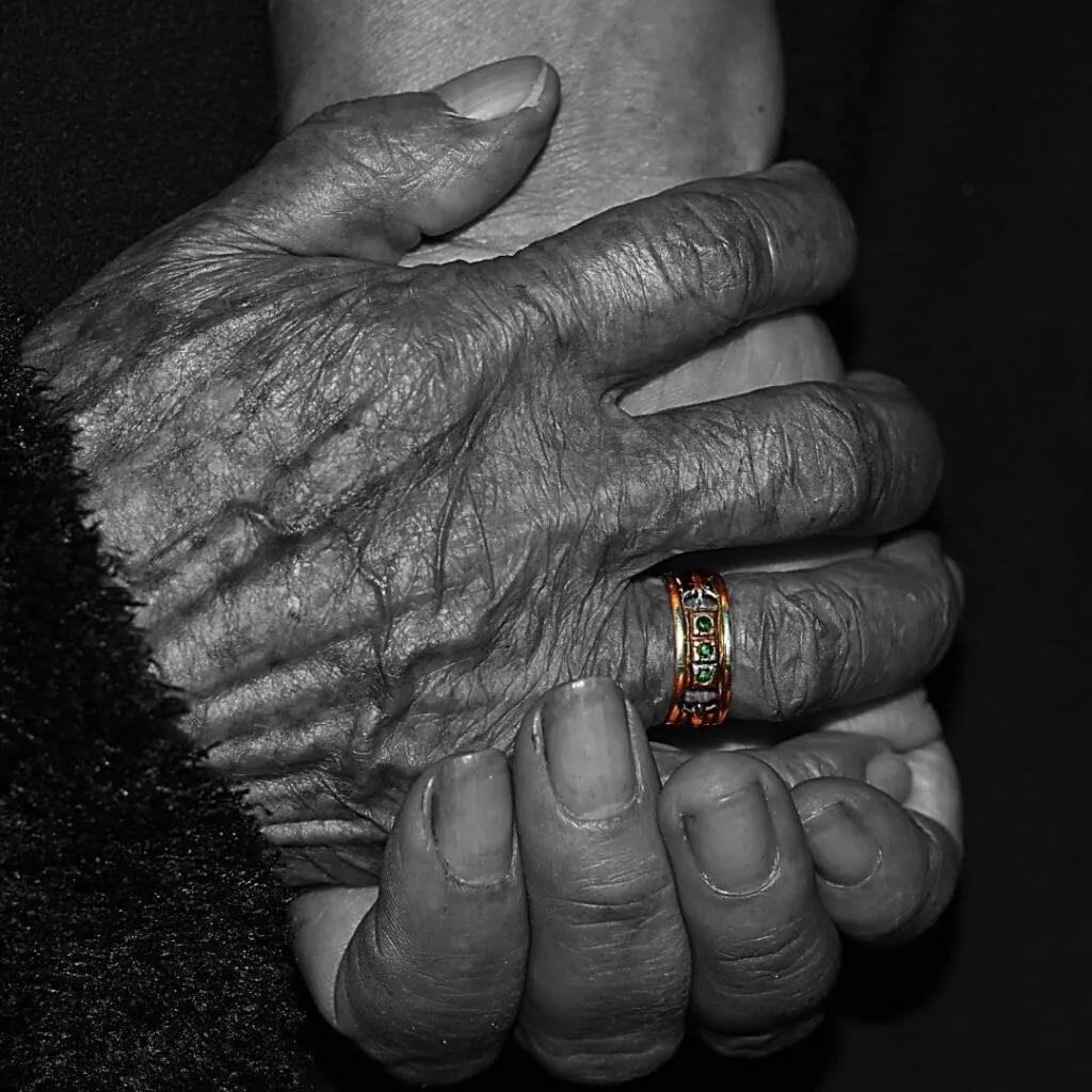 an old woman's hands with a gold ring held by a younger hand