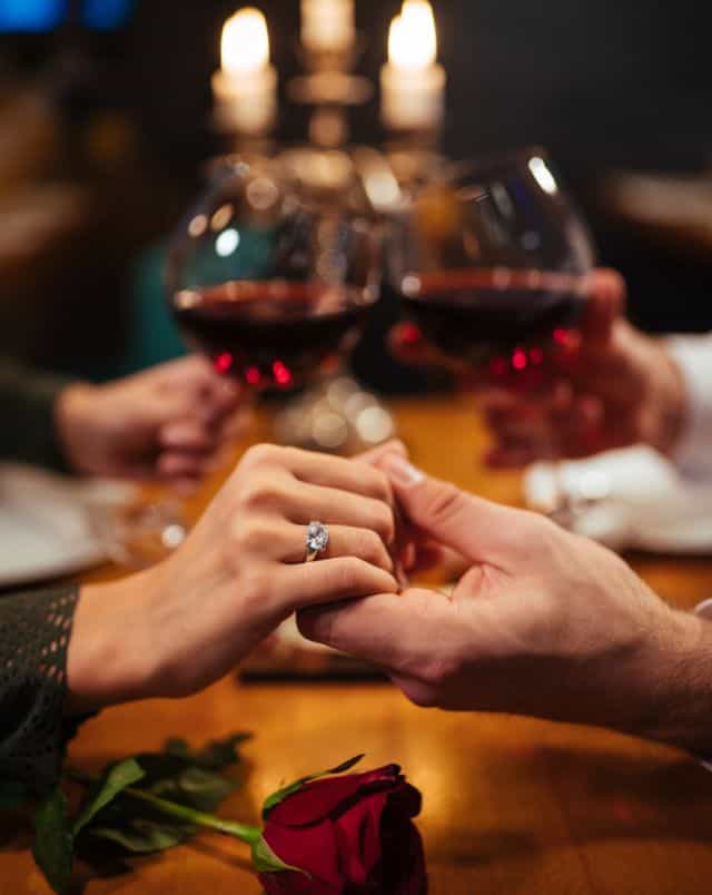 Close up shot of people holding hands and toasting wine glasses at a candlelit dinner at one of the most romantic resorts in Wisconsin