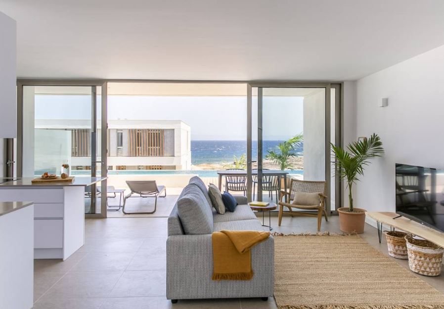 living room with sofa, TV, open kitchen and balcony with sea view at Kora Nivaria Beach in Abades, Tenerife