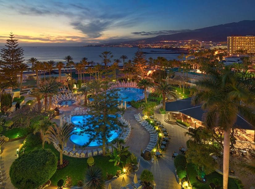 the grounds of H10 Las Palmeras in Playa de las Americas, Tenerife at night with pools and sea view