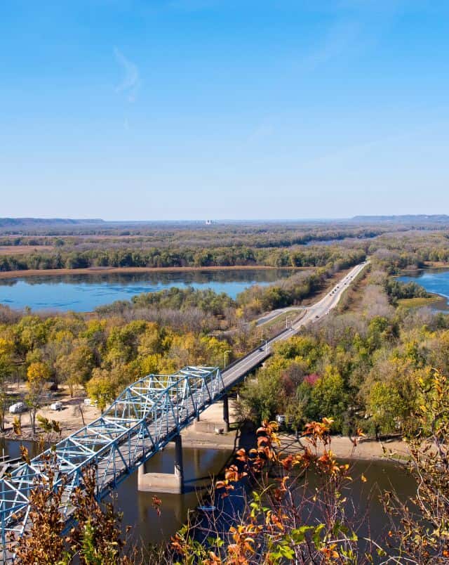 things to do in Wisconsin for kids, View from a hillside of a road built on a bridge over a river leading off into the distance through an area of lakes and trees all under a wide open blue sky