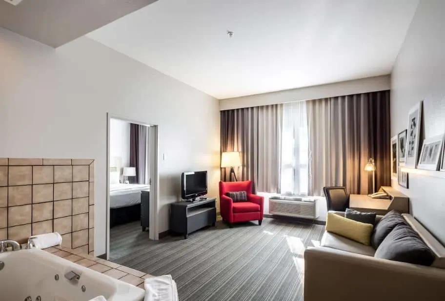 a living room area with jacuzzi and a bedroom at Country Inn & Suites by Radisson - Fond du Lac