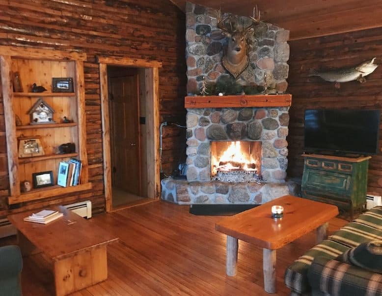 living room with fire place and cozy sofa at the Charming, vintage, log cabin on beautiful Spider Lake chain in Hayward, Wisconsin